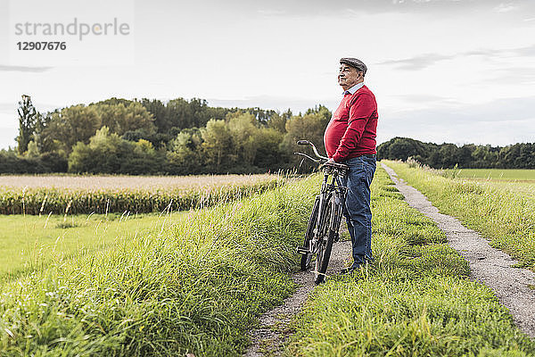 Senior man with bicycle in rural landscape