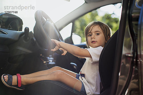 Portrait of little boy sitting on driver's seat in a car