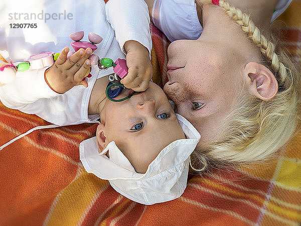 Girl playing with baby girl on blanket