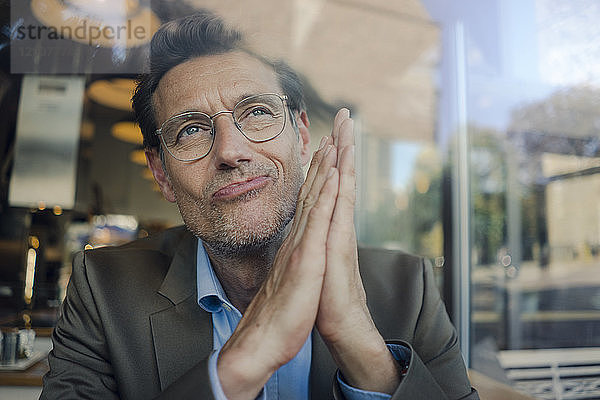 Mature businessman sitting in coffee shop  smiling