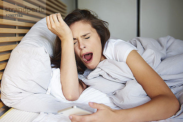 Portrait of yawning woman lying in bed