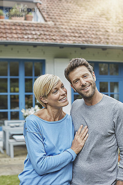 Portrait of smiling couple standing in front of their home