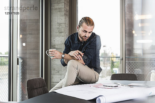 Young businessman looking at plan on desk in office