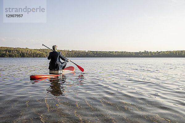 Back view of businessman paddling on lake
