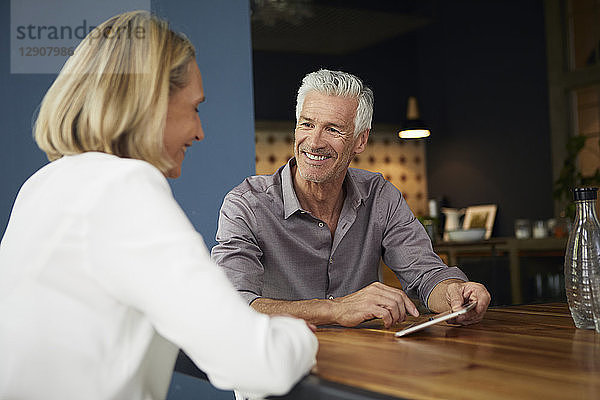 Smiling mature couple with tablet at home