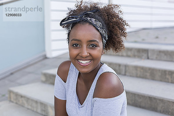 Portrait of smiling young woman wearing hair-band sitting on stairs