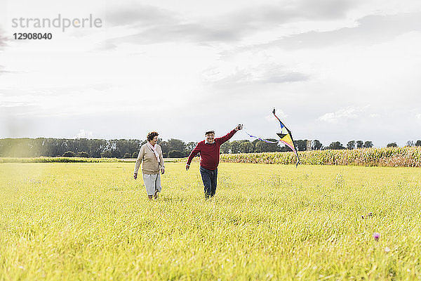 Happy senior couple flying kite in rural landscape