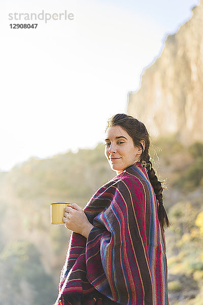 Spain  Alquezar  portrait of smiling young woman with coffee mug in nature