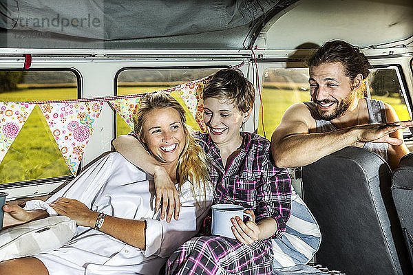 Happy friends inside a van enjoying coffee