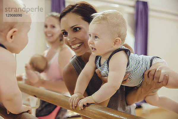 Mother holding up her baby to barre in dance studio