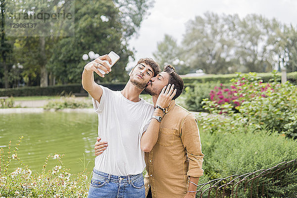 Young gay couple taking selfie with smartphone at city park