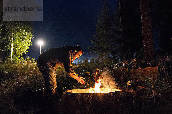 Finland  Man warming up at a camp fire on a camping ground