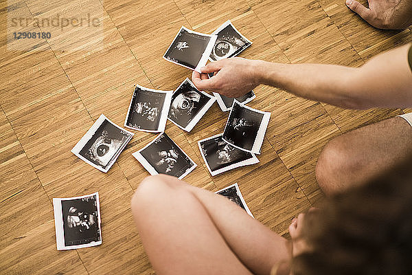 Couple with ultrasound scans on wooden floor
