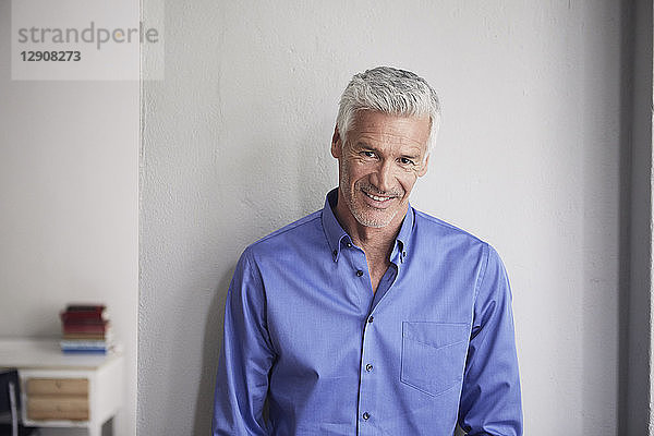Portrait of smiling mature man leaning against wall