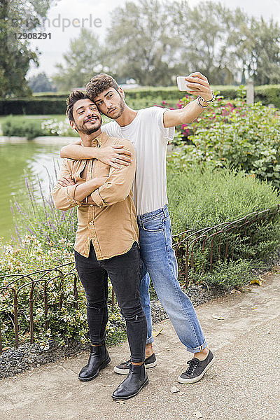 Portrait of young gay couple taking selfie with smartphone at city park