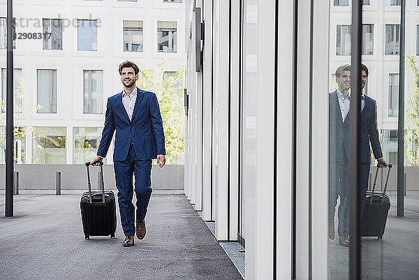 Smiling businessman with baggage in the city on the move