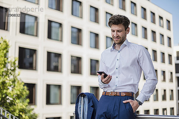 Businessman standing in the city using cell phone