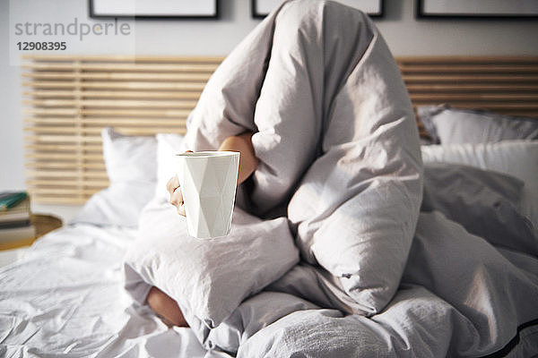 Woman hidden under blanket demanding coffee