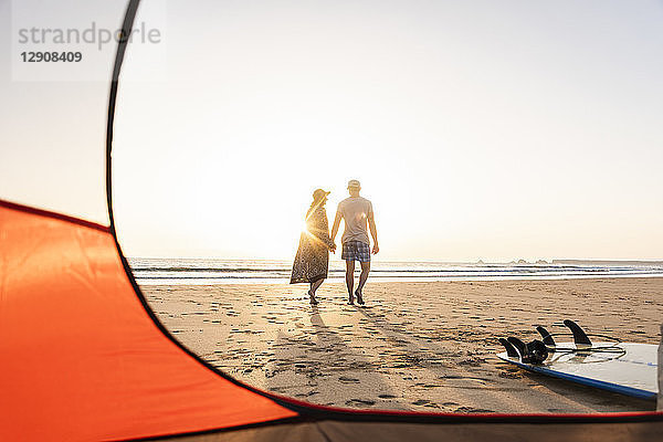 Romantic couple camping on the beach  doing a beach stroll at sunset