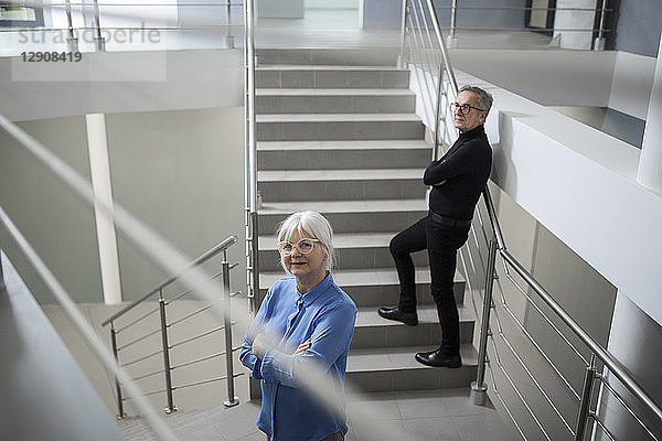 Two senior colleagues standing on office stairs