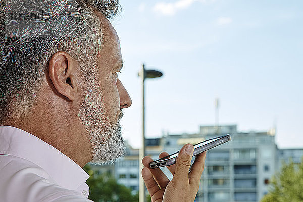 Close-up of mature man using smartphone outdoors