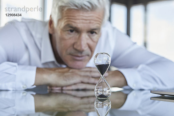 Businessman sitting at desk  watching hourglass