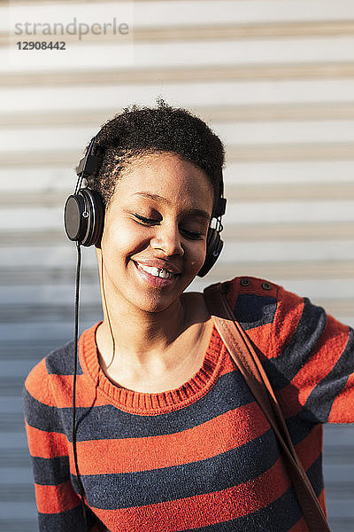 Portrait of smiling young woman listening music with headphones