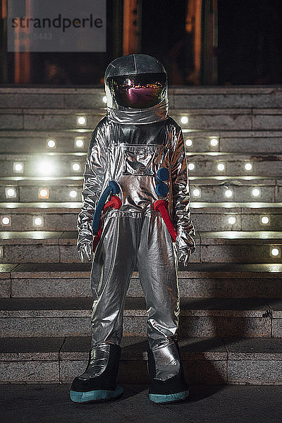 Spaceman standing at illuminated stairs at night