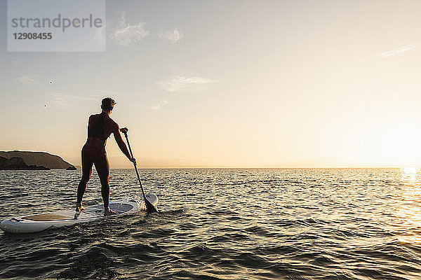 Young man on paddleboard at sunset