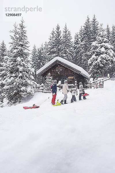 Austria  Altenmarkt-Zauchensee  family with sledges at wooden house at Christmas time