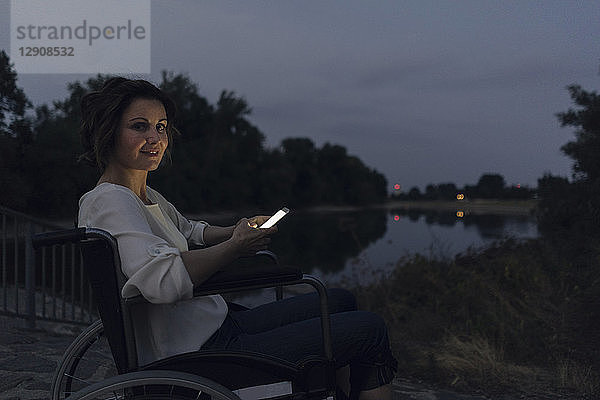 Disabled woman sitting in wheelchair  using smartphone