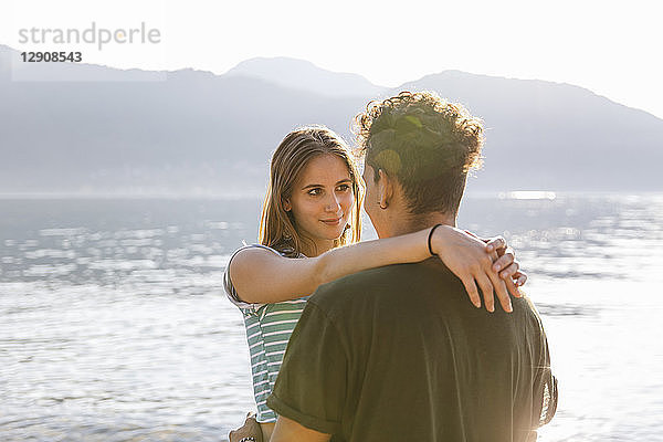 Affectionate young woman embracing boyfriend at the lakeside