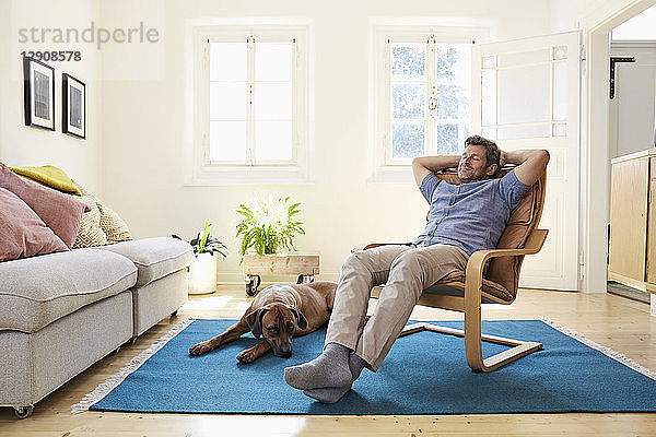 Man relaxing at home with his dog by his side
