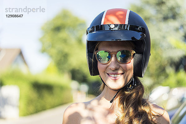 Portrait of smiling woman wearing sunglasses and motorcycle helmet