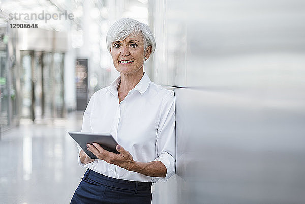 Portrait of smiling senior businesswoman holding tablet