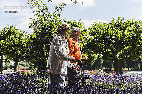 Senior couple walking in park  woman using wheeled walker