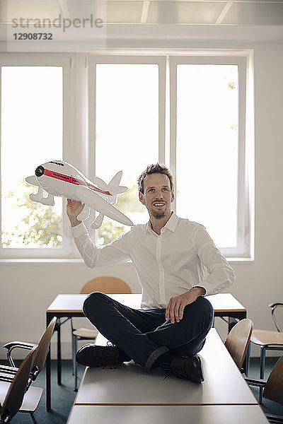Businessman playing with inflatable airplane in office