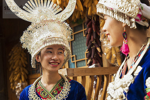 China  Guizhou  two smiling young Miao women wearing traditional dresses and headdresses