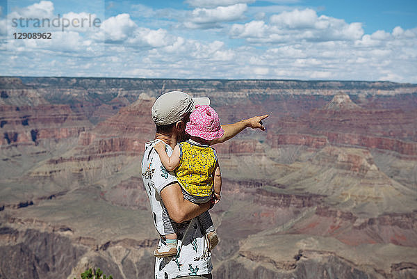 USA  Arizona  Grand Canyon National Park  father and baby girl enjoying the view  rear view