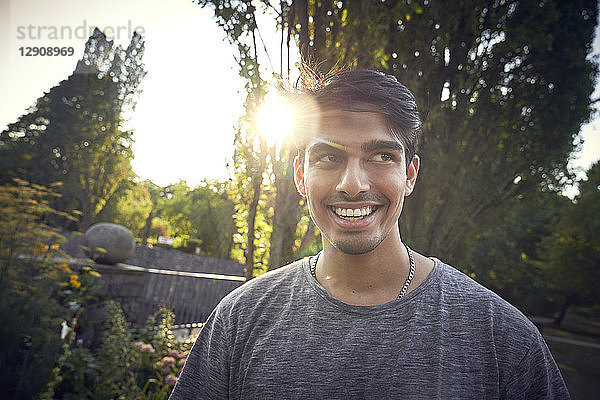 Portrait of a young man in a park at sunset  smiling