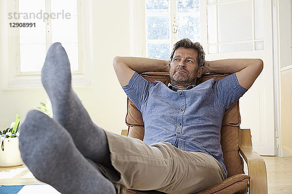 Man sitting in arm chair with feet up  daydreaming