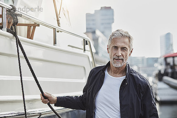 Confident mature man at a marina next to a yacht