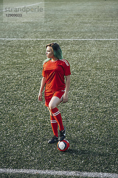 Young woman standing on football ground with the ball