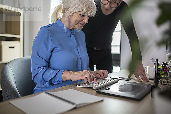 Two senior colleagues working together at desk in office