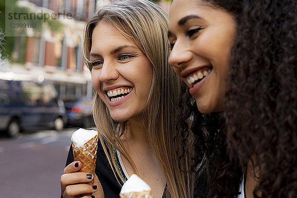 Two laughing girlfriends having fun  eating ice cream