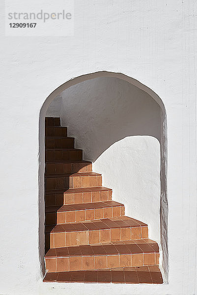 Spain  Menorca  white wall with arch and staircase behind