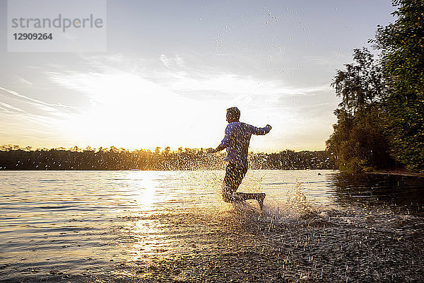 Man running into lake by sunset