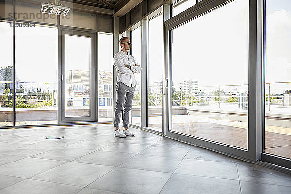 Businessman standing in empty room looking out of panorama window