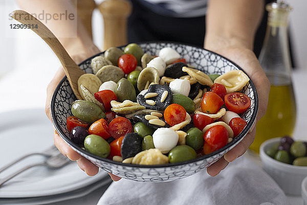 Woman showing mediterranean orecchiette with tomato  olives and mozzarella