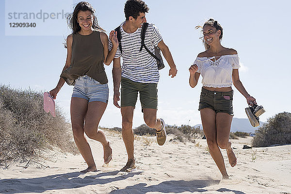 Friends having fun  running barefoot on the beach